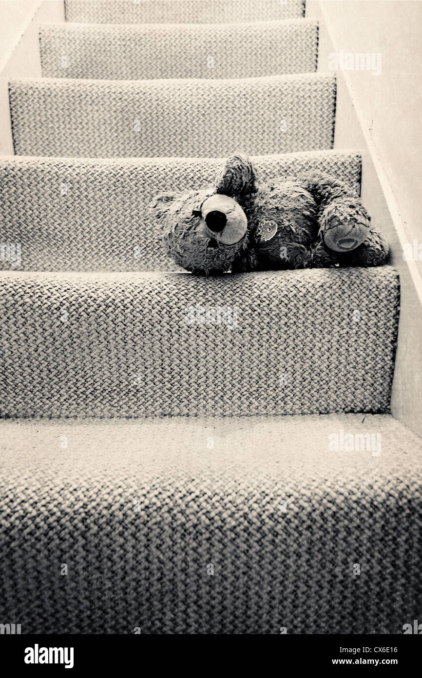 A well loved teddy lying on the stairs (sepia toned) Stock Photo