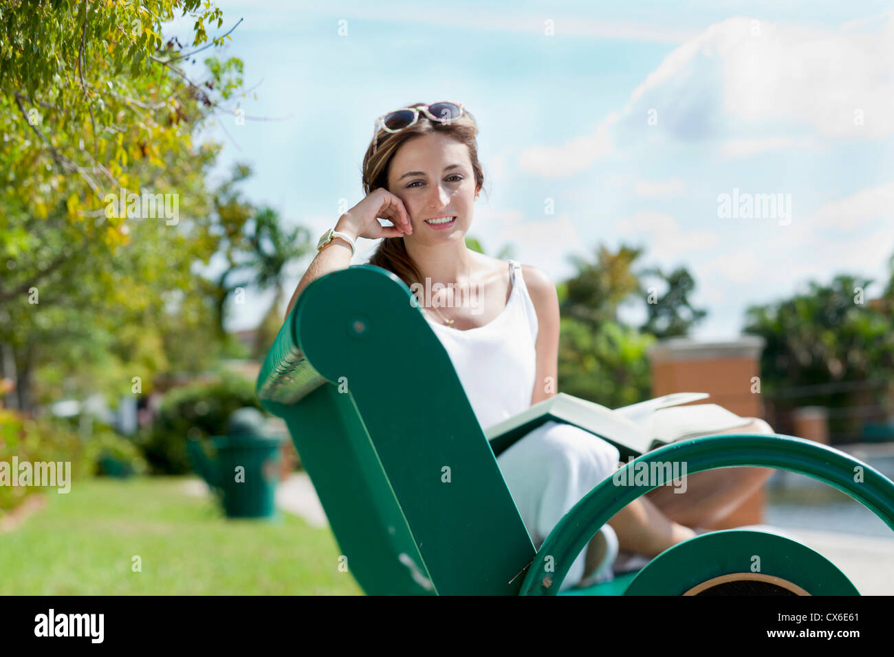 A woman relaxing on a park bench with a book Stock Photo - Alamy