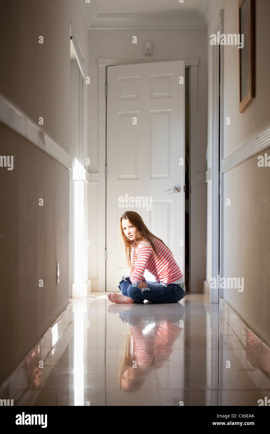 Girl sitting cross-legged in hallway Stock Photo
