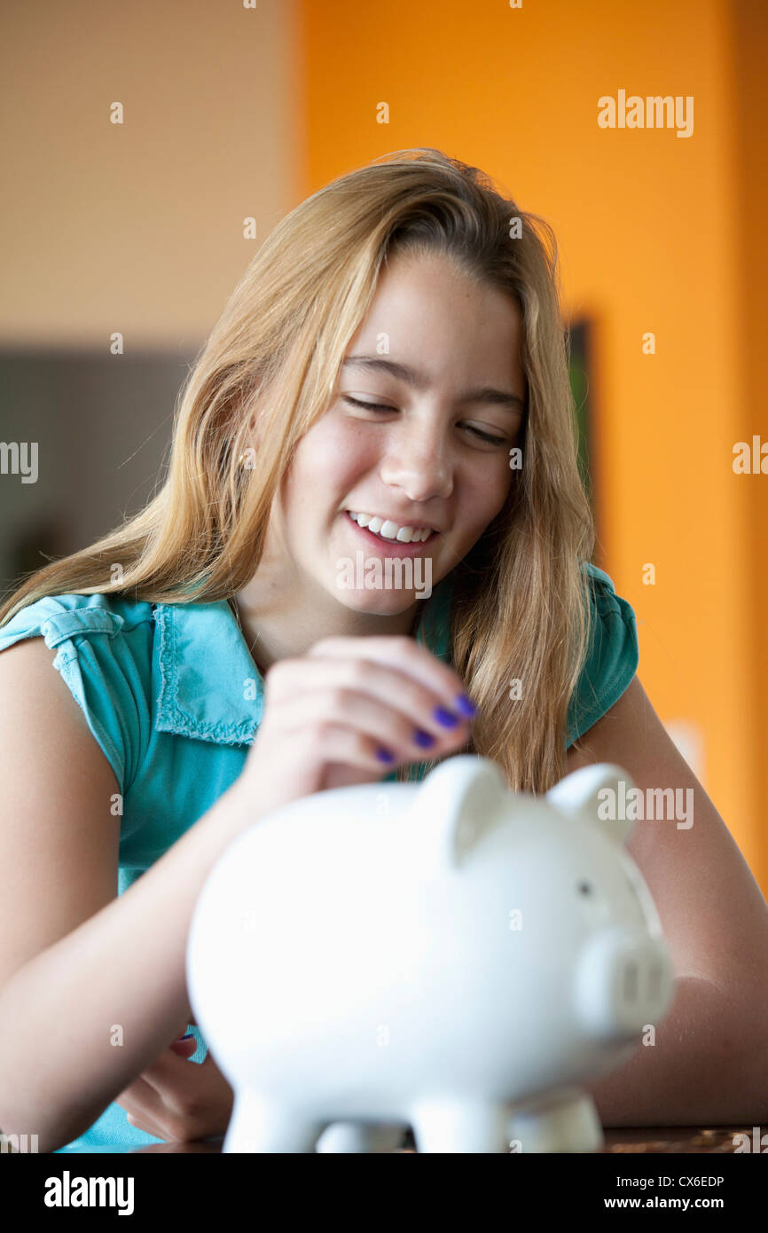 Girl putting coin in piggy bank Stock Photo - Alamy