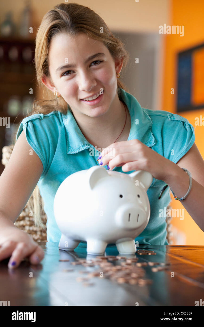 Girl puts coin in piggy bank Stock Photo - Alamy
