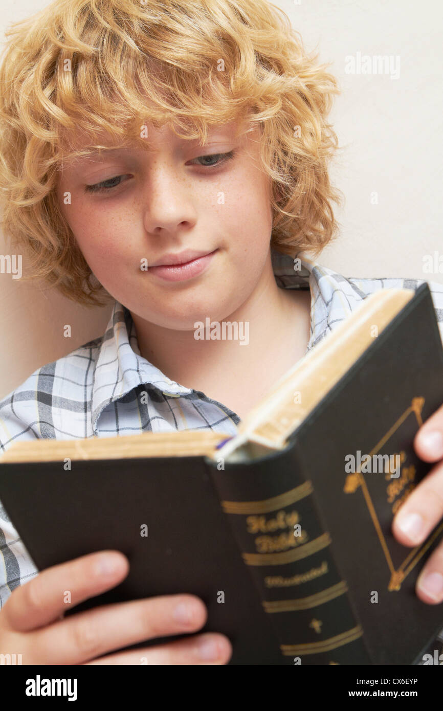 Boy Reading Bible At Home Stock Photo
