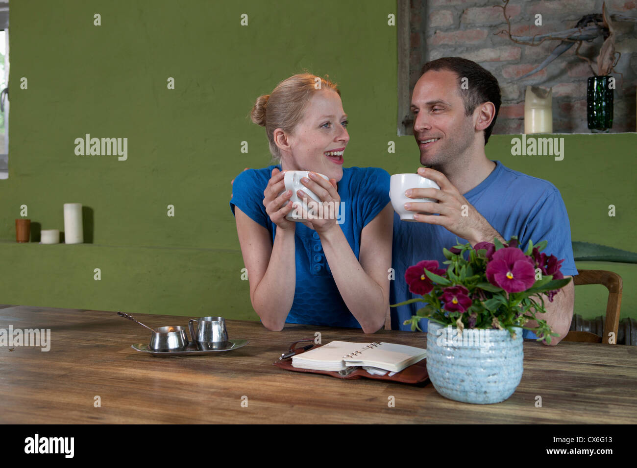 A couple sitting at a dining table with a personal organizer, talking excitedly Stock Photo