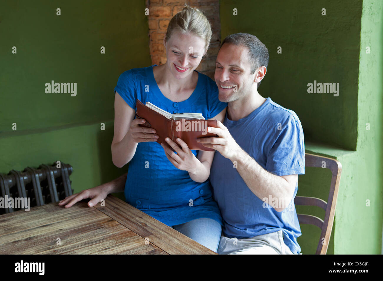 A couple reading a personal organizer together and smiling Stock Photo