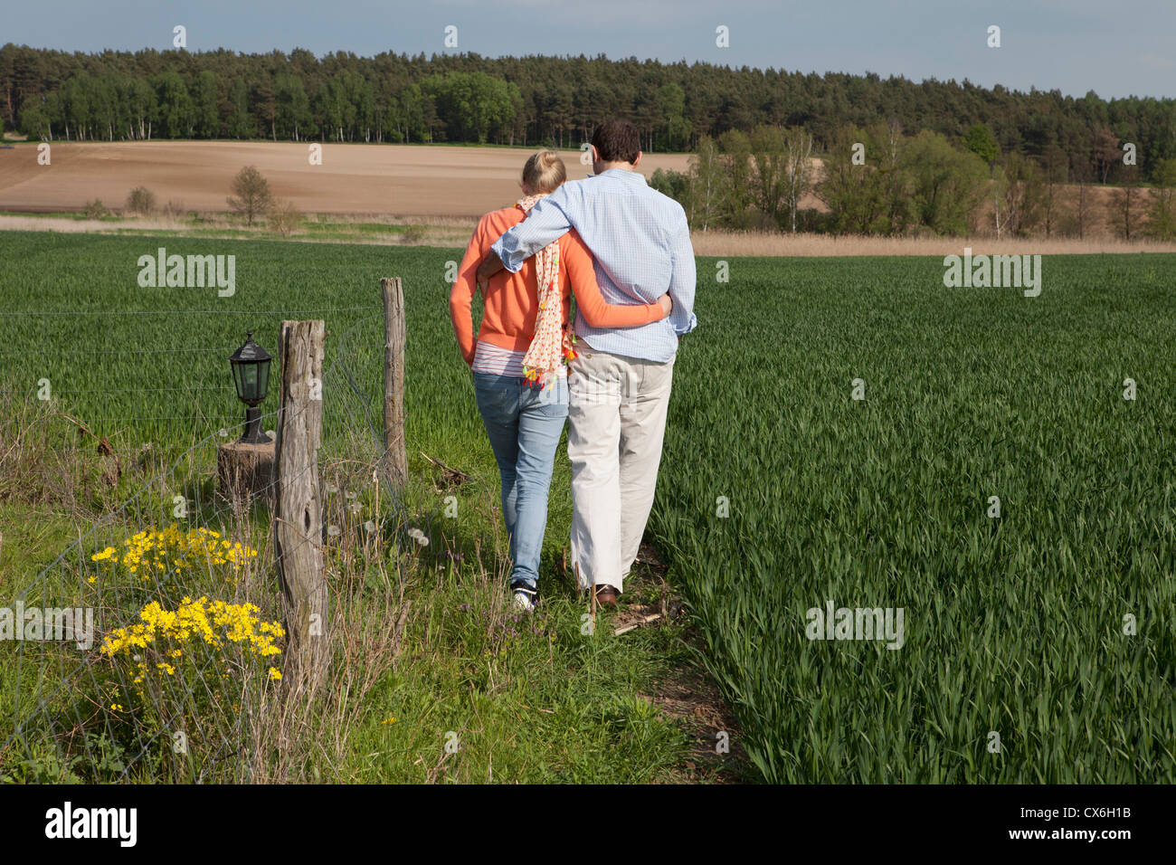 A couple walking side by side in a field, rear view Stock Photo - Alamy