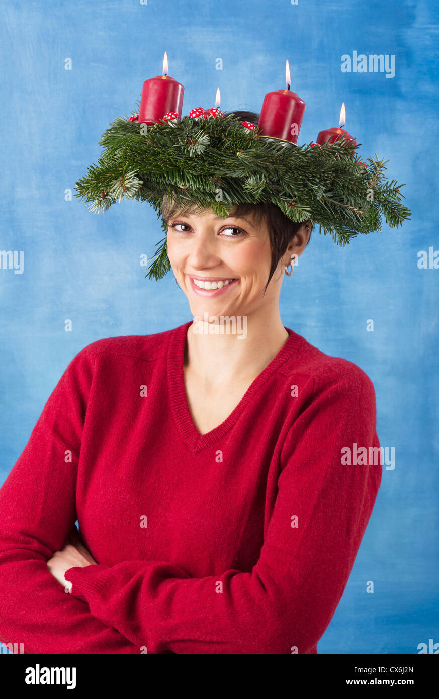 Smiling young woman wearing advent wreath on her head, four candles are