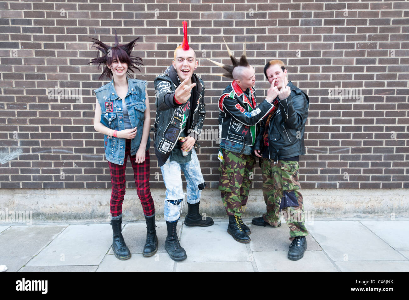 Punk rockers pose for a portrait against a brick wall and pull interesting faces Stock Photo