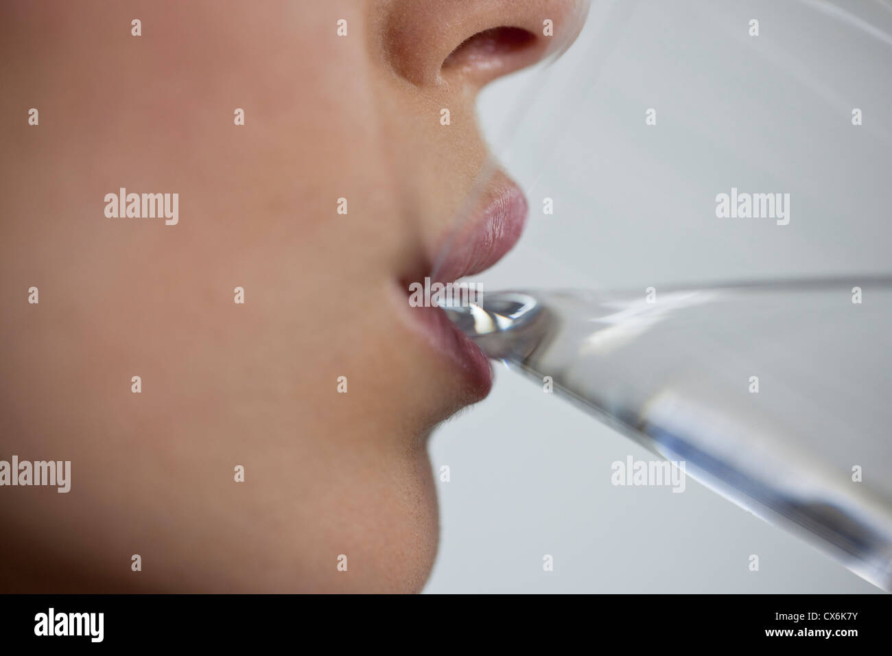 A young woman drinking a glass of water, close up of mouth Stock Photo