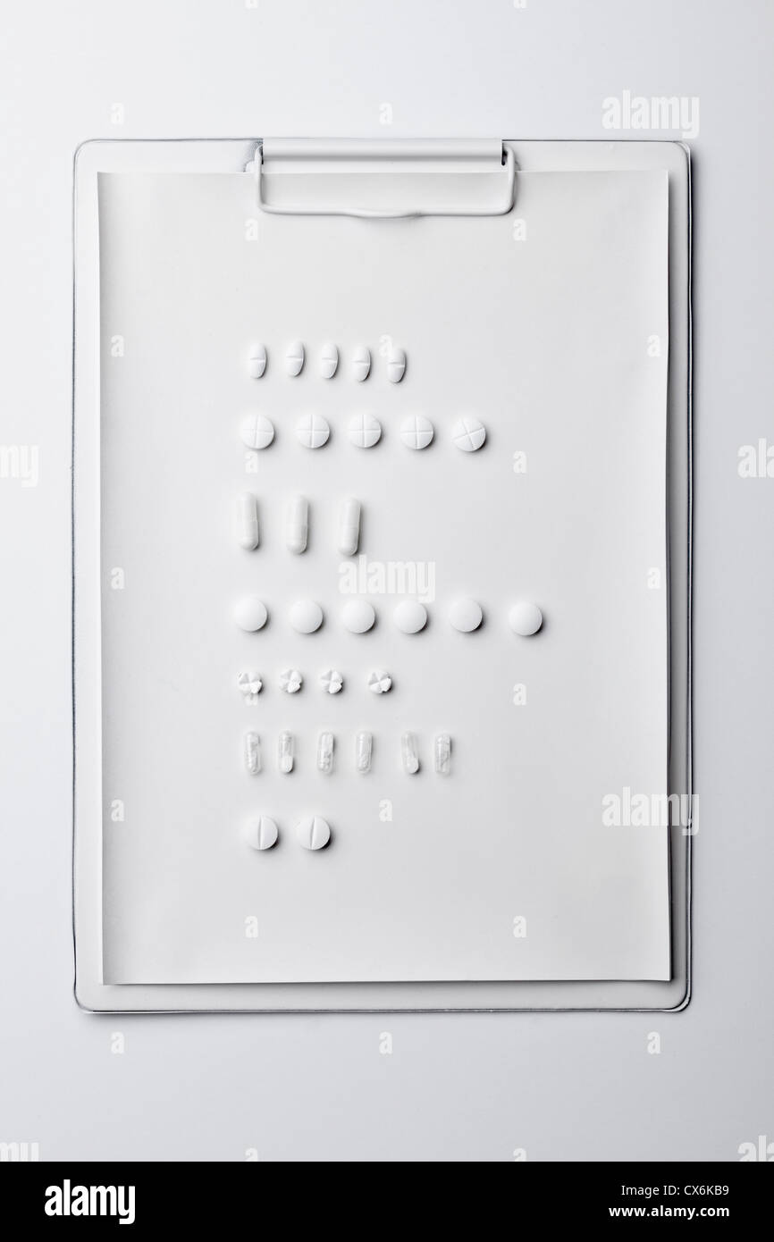 Various white pills and capsules in rows on a clipboard Stock Photo