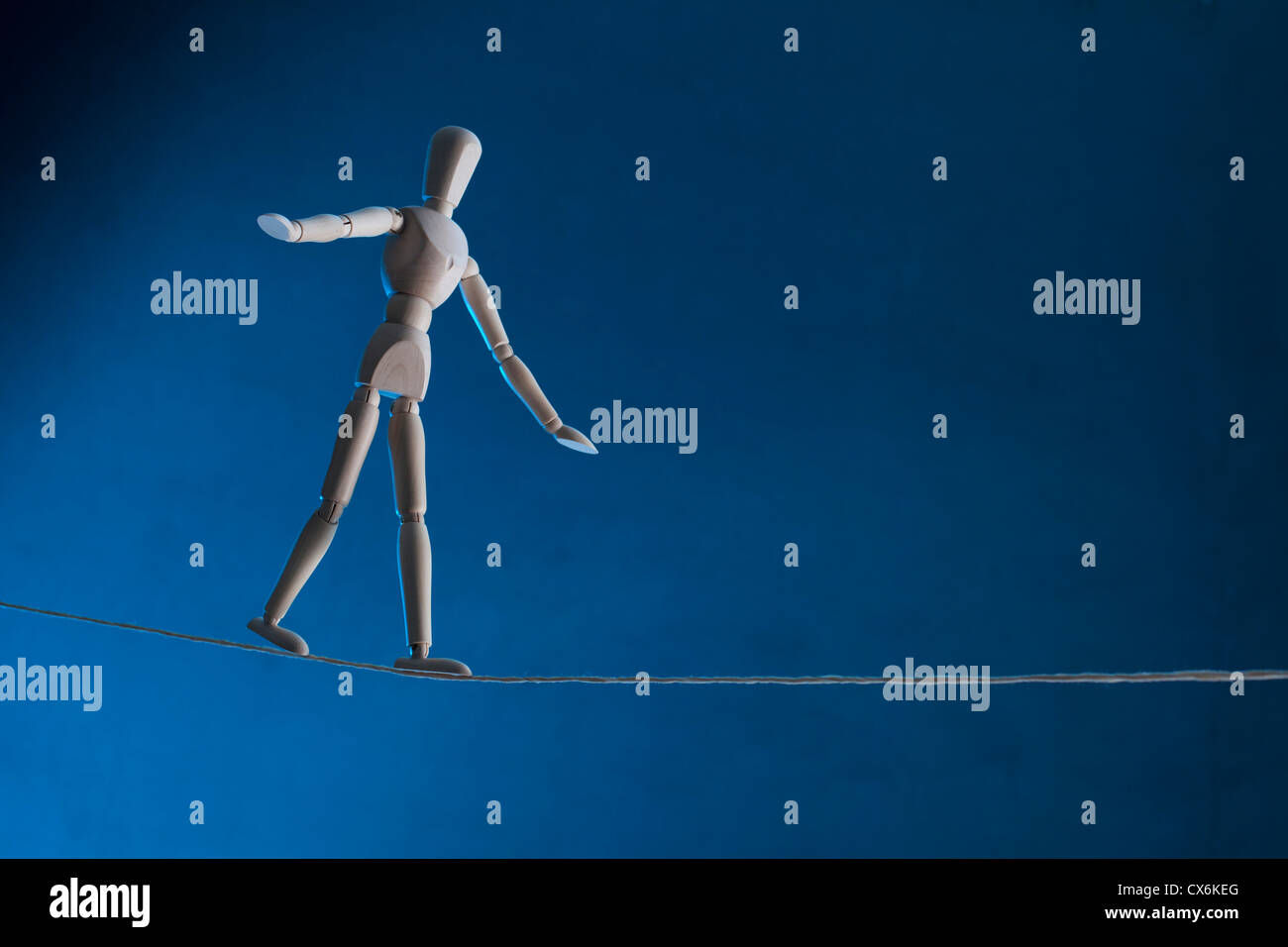 An artist's figure walking a tightrope Stock Photo