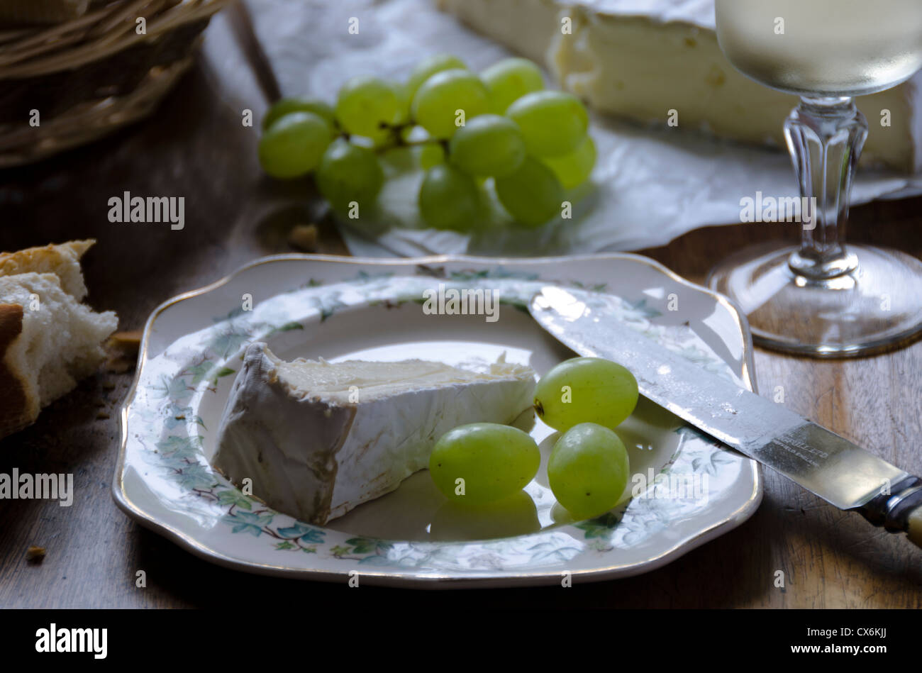 A plate of ripe French Brie with fresh green grapes, wine and bread Stock Photo