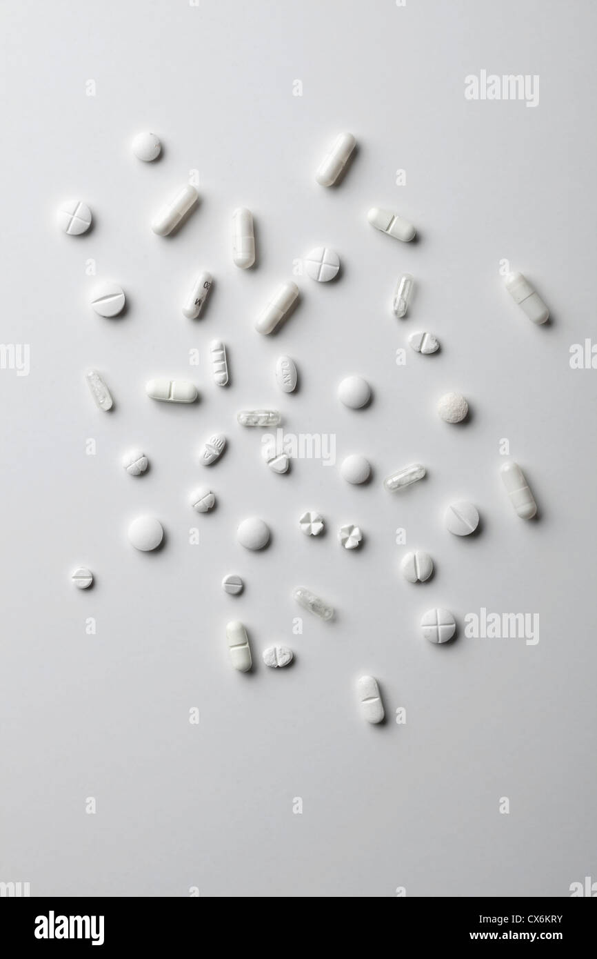 Various white pills and capsules spread out on a white surface Stock Photo