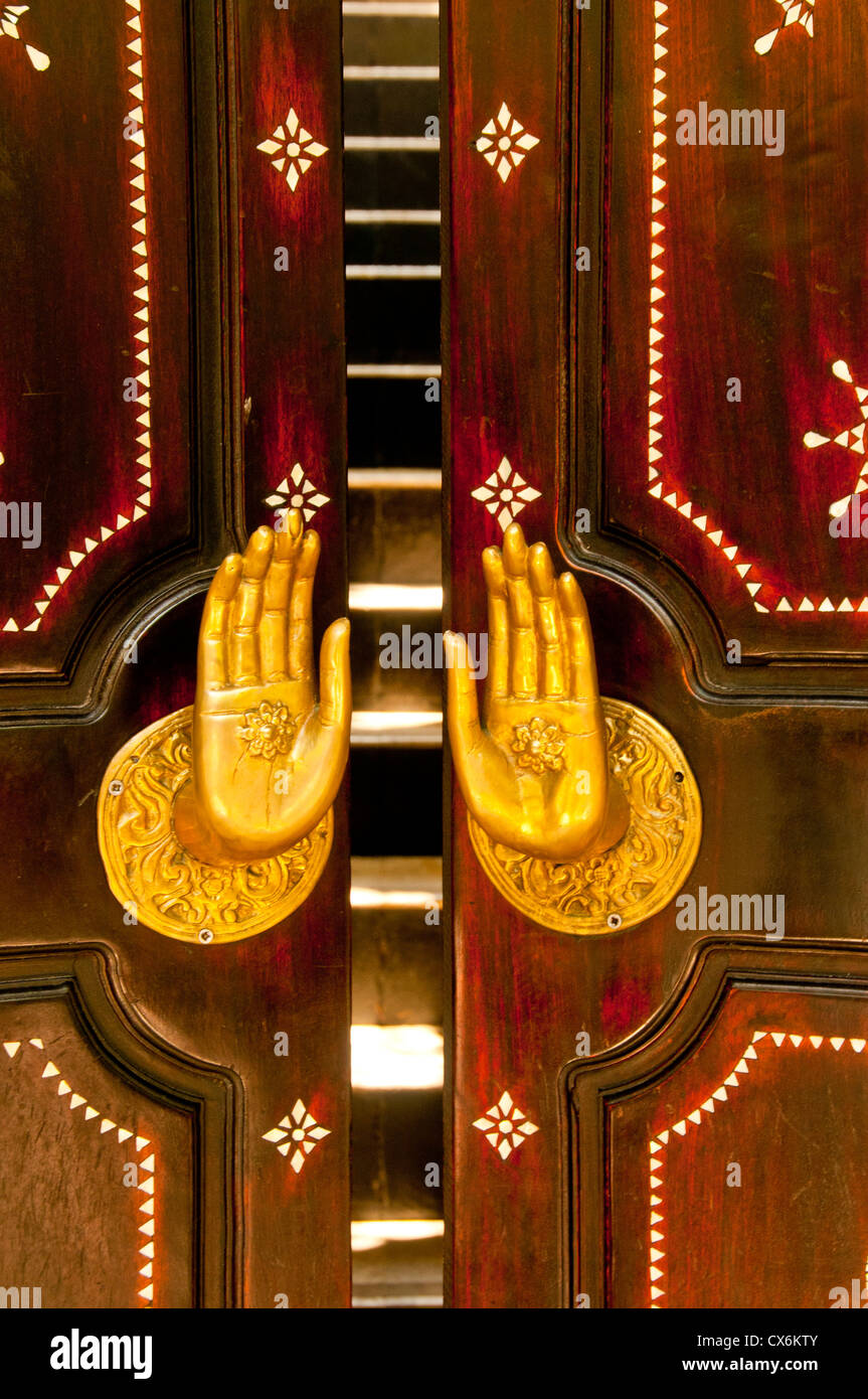 USA, Wooden carved door with golden brass hands-handles in the door way. Riviera Maya, Mexico Stock Photo