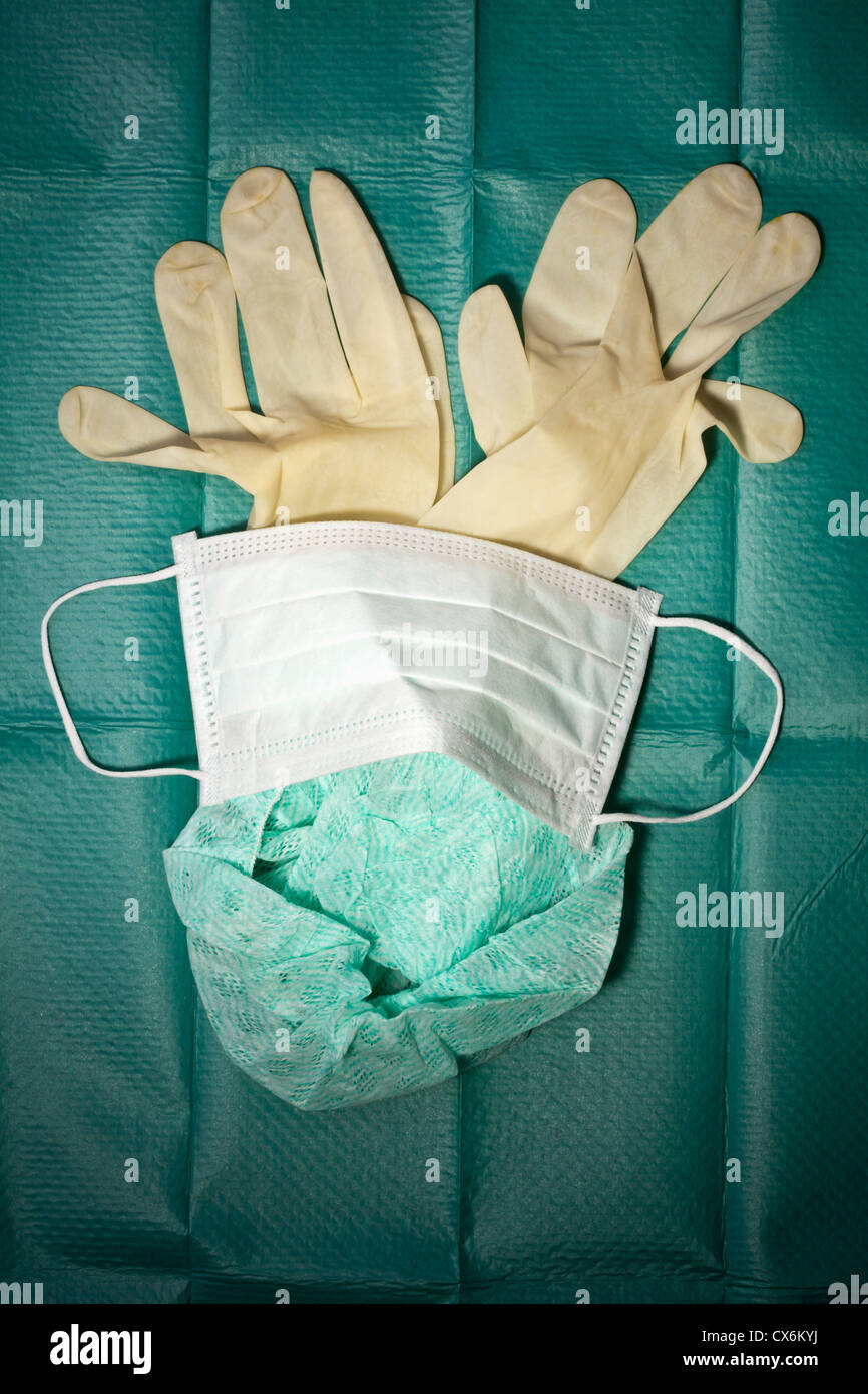 Surgical mask, cap and gloves arranged on a surgical drape Stock Photo