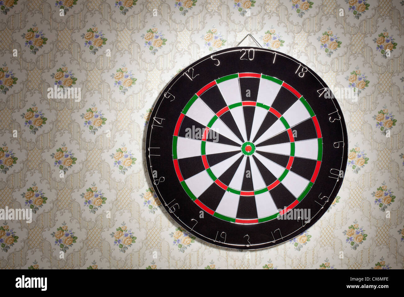 A dartboard hanging on a wallpapered wall Stock Photo