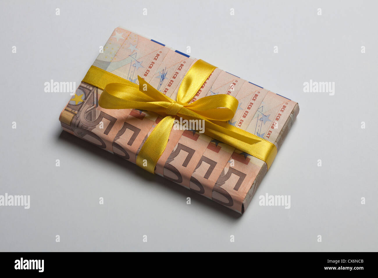 Fifty Euro banknotes used to wrap a gift with a yellow bow Stock Photo