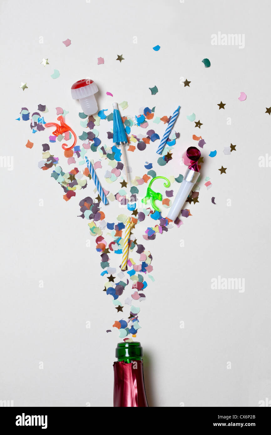 Confetti and party supplies spraying out of a champagne bottle Stock Photo
