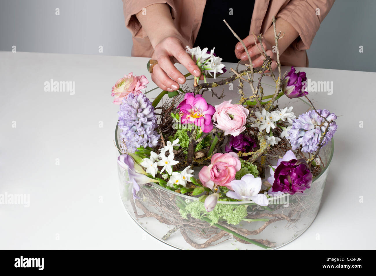 A florist arranging flowers in a glass bowel vase Stock Photo