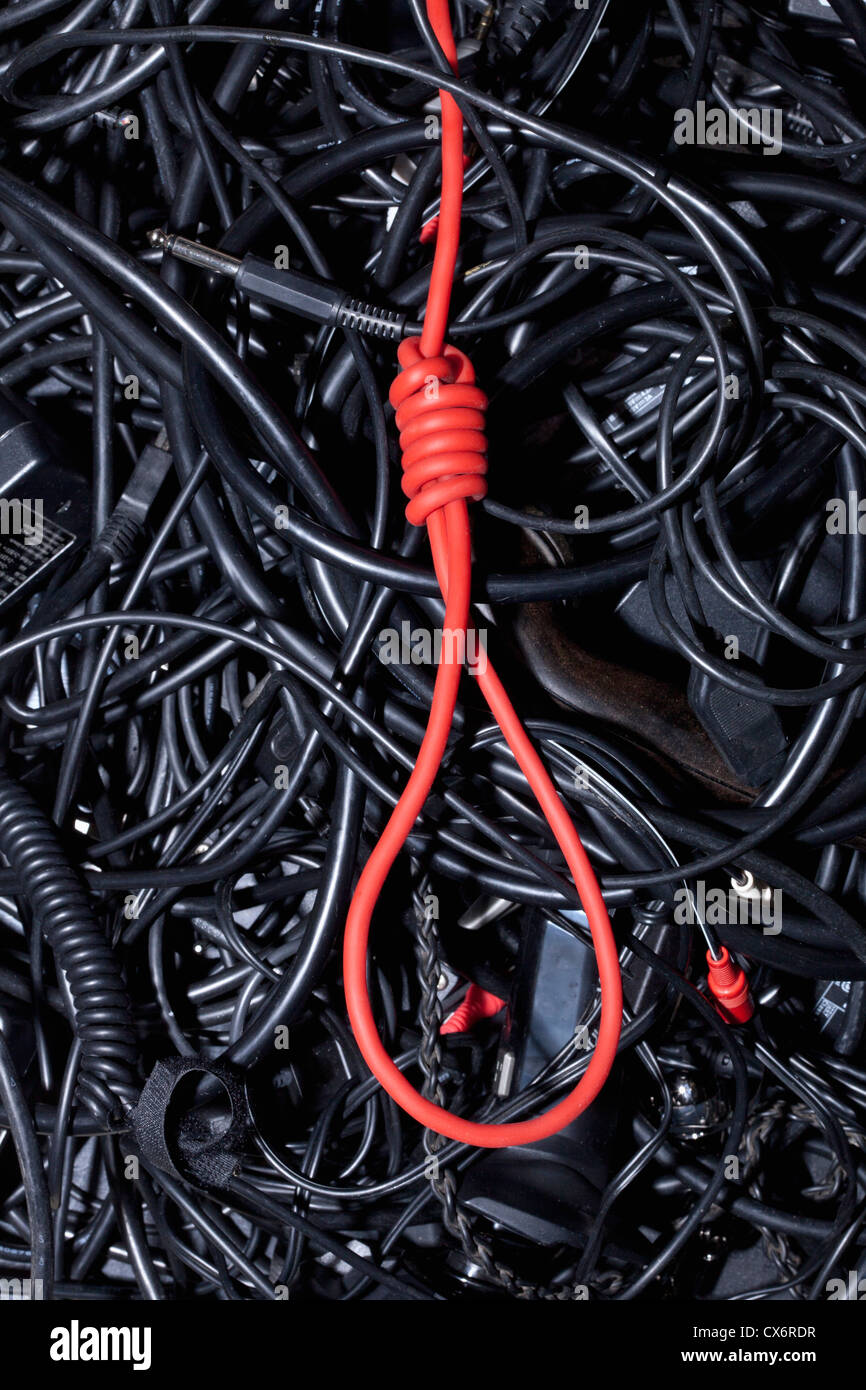 A red cord tied into a noose amongst tangled black cables and cords Stock Photo