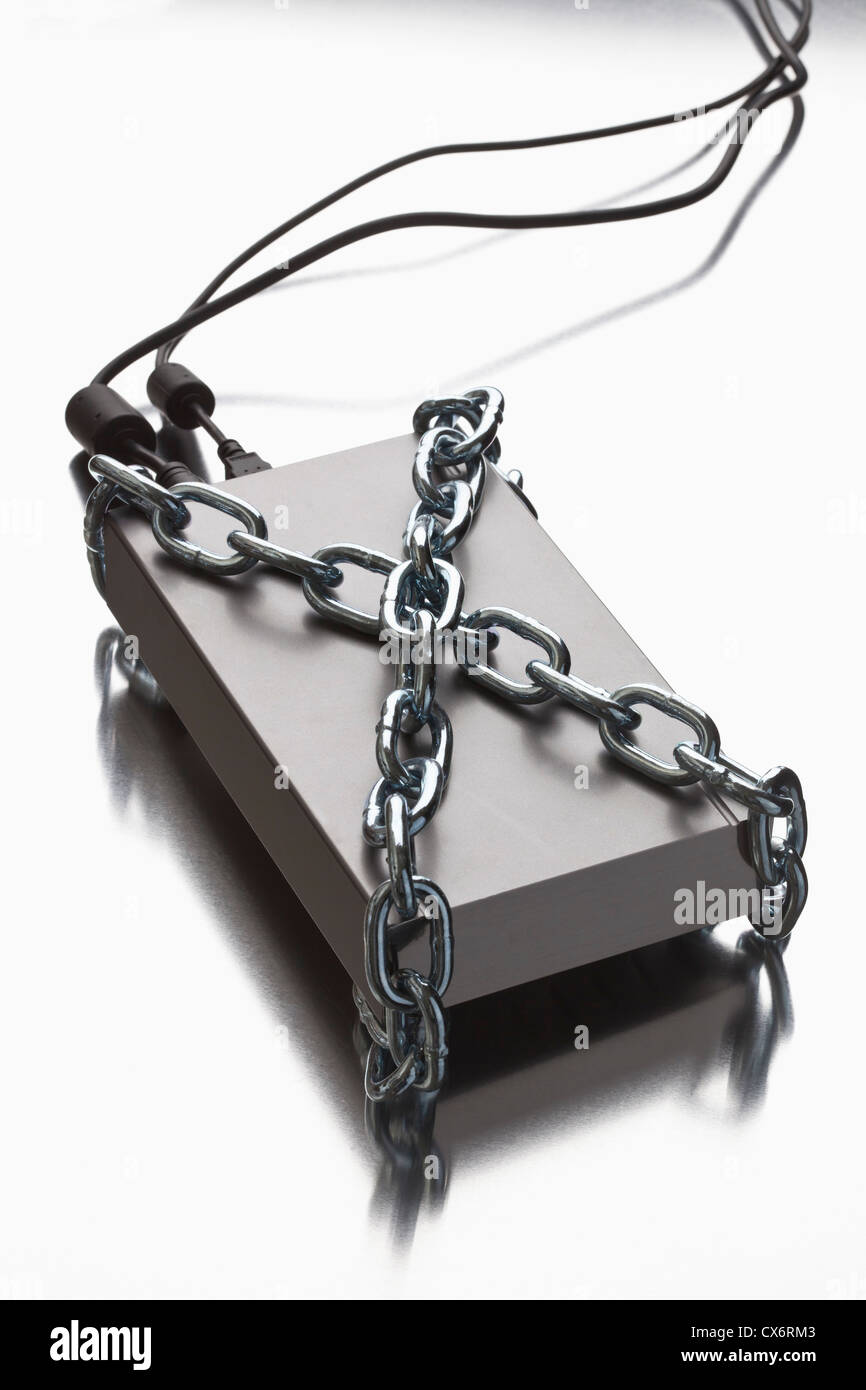 A thick metal chain wrapped around an external hard drive Stock Photo
