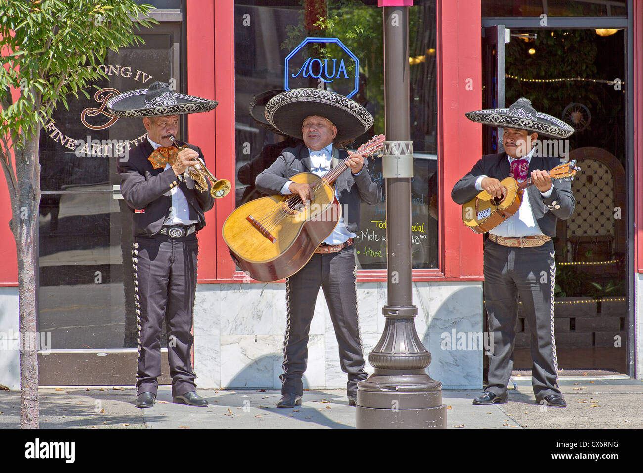 A three piece mariachi band plays for tips in front of a restaurant in downtown Asheville, North Carolina on August 26, 2012 Stock Photo