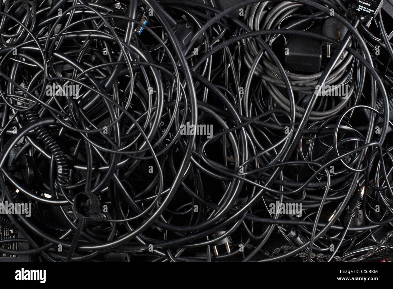 A mess of tangled black cords and cables Stock Photo