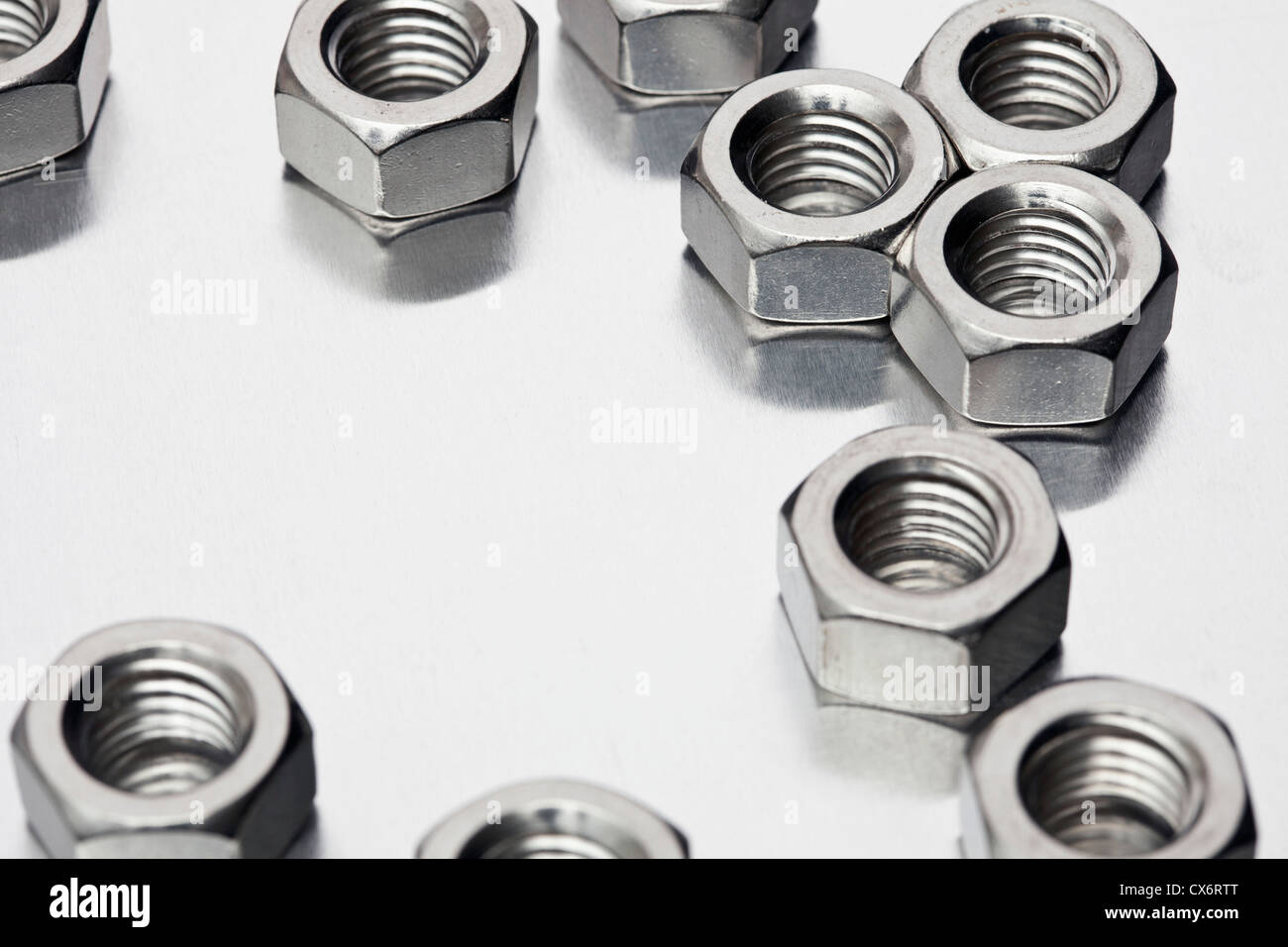 Shiny metal nuts on a reflective surface Stock Photo