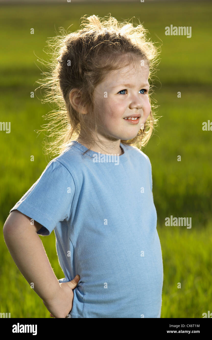 A young girl standing in a field and looking away Stock Photo