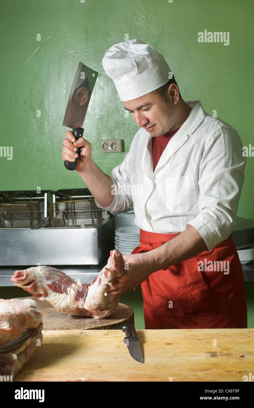 A butcher chopping meat with a cleaver Stock Photo Alamy