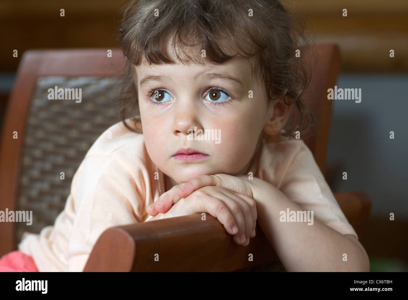 A young girl sitting on a chair and looking away Stock Photo - Alamy