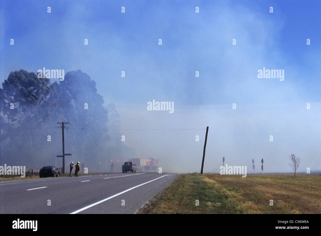 Fire fighters tackling forest fire by the road, Canterbury, South Island, New Zealand Stock Photo