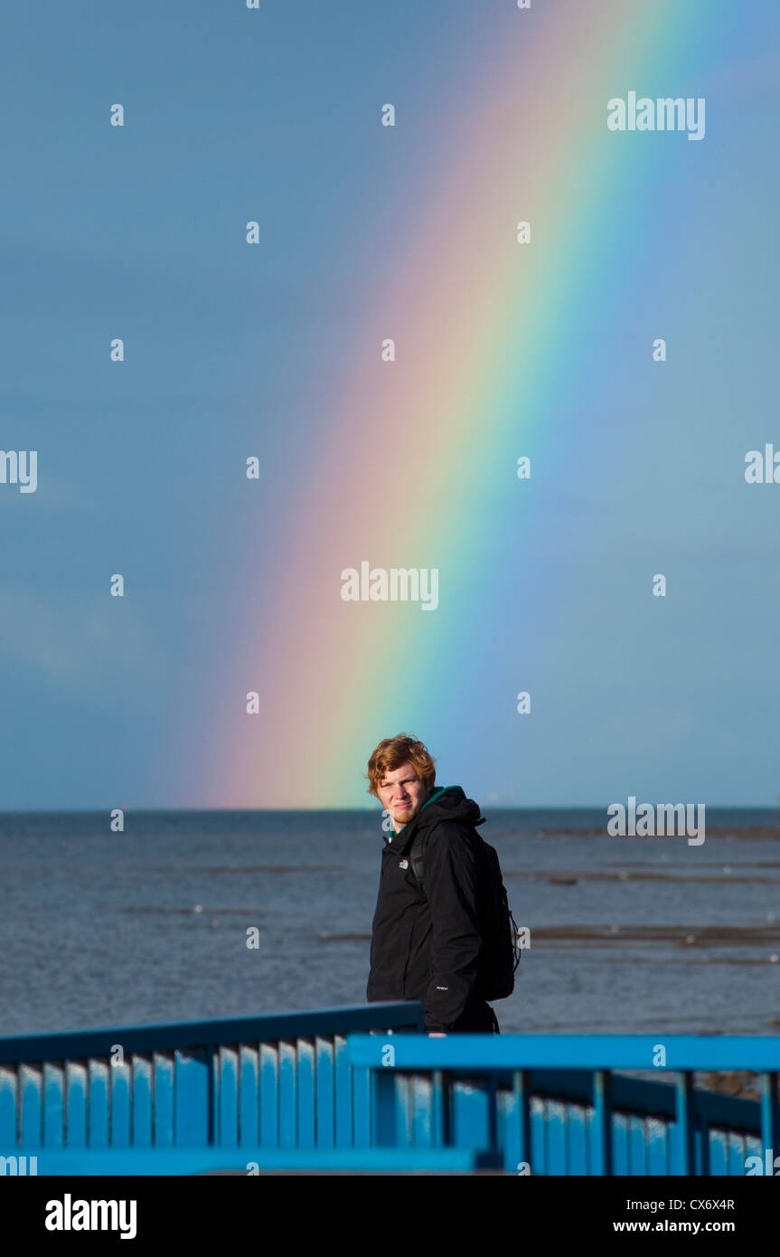Ginger haired boy looking at rainbow over Belfast Lough Stock Photo