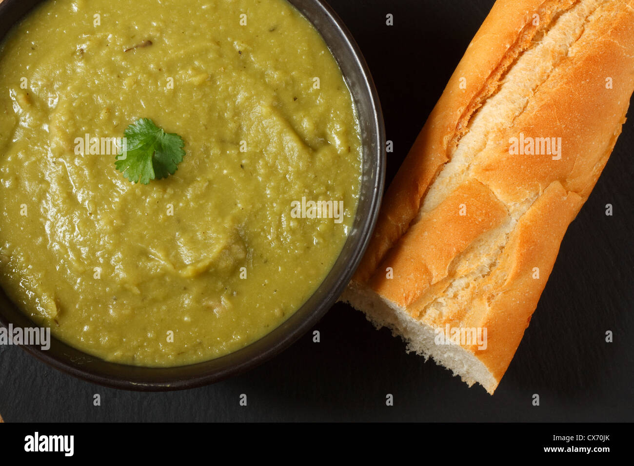 Bowl of homemade pea and ham soup in with crusty french bread Stock Photo