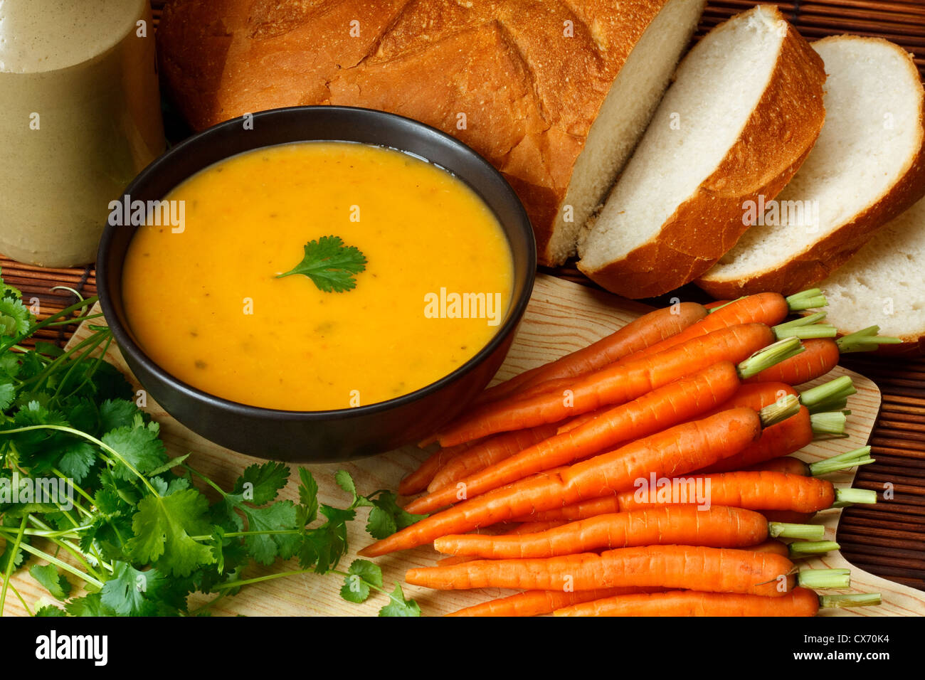 Dish of homemade Carrot and coriander soup in kitchen setting surrounded by ingredients and