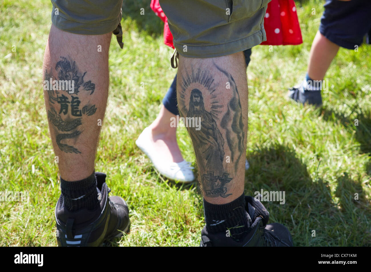 Tattoos on back of mans legs of Savior and dragon Stock Photo