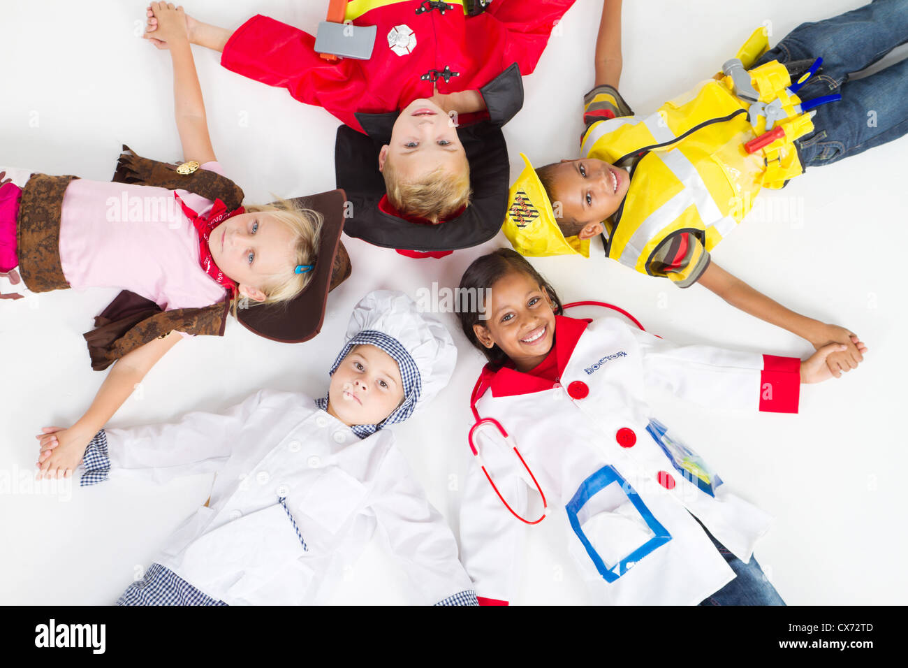 group of kids in various uniforms lying on floor Stock Photo