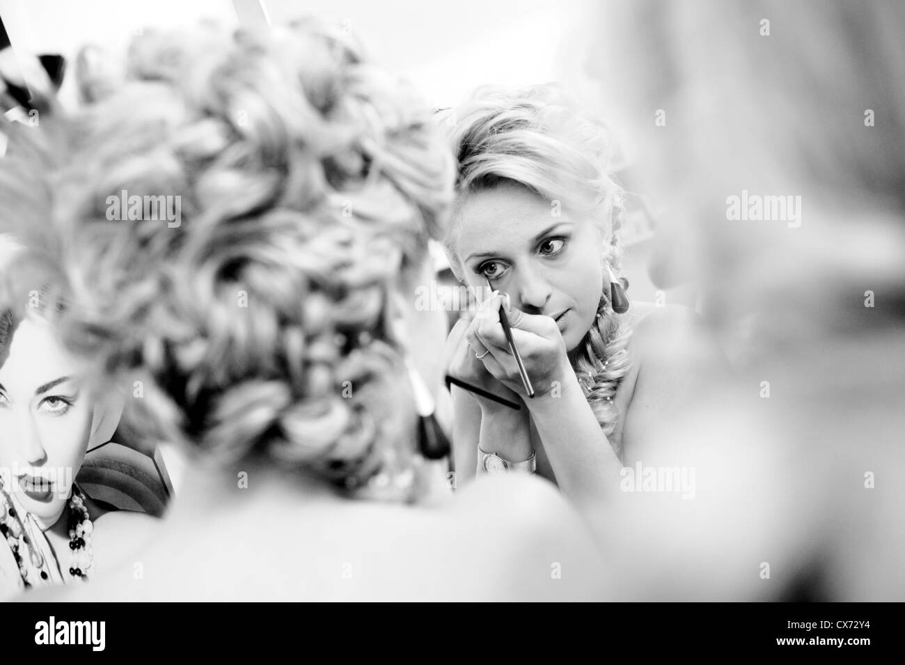 Blond girl applying eyeliner Stock Photo