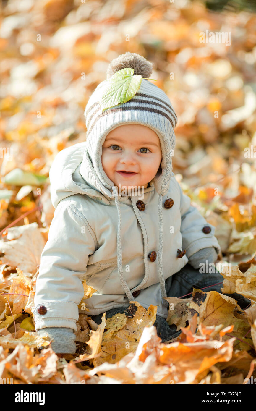 One and a half years cute baby boy siting on the autumn leaves ...