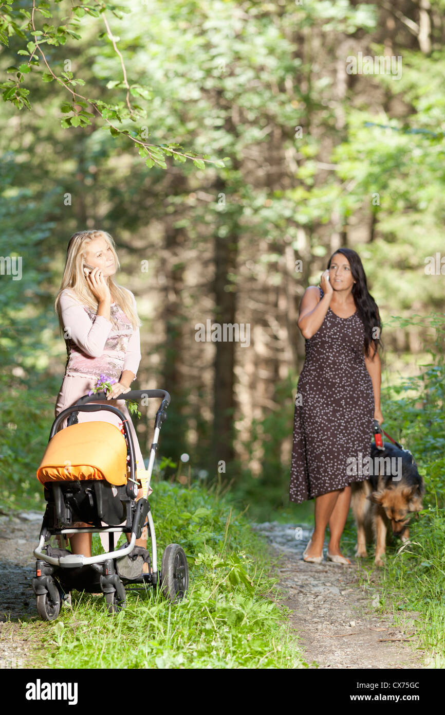 Two telephoning women with child and dog are strolling Stock Photo