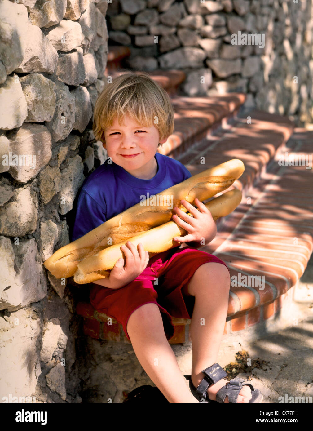 LITTLE BOY HOLDING FRENCH BREAD Stock Photo