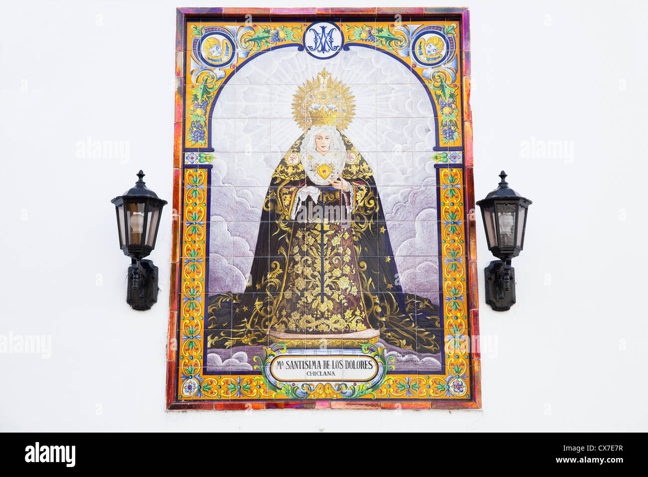 A Religious Figure On Tile On A White Wall With Mounted Lights; Chiclana De La Frontera, Andalusia, Spain Stock Photo