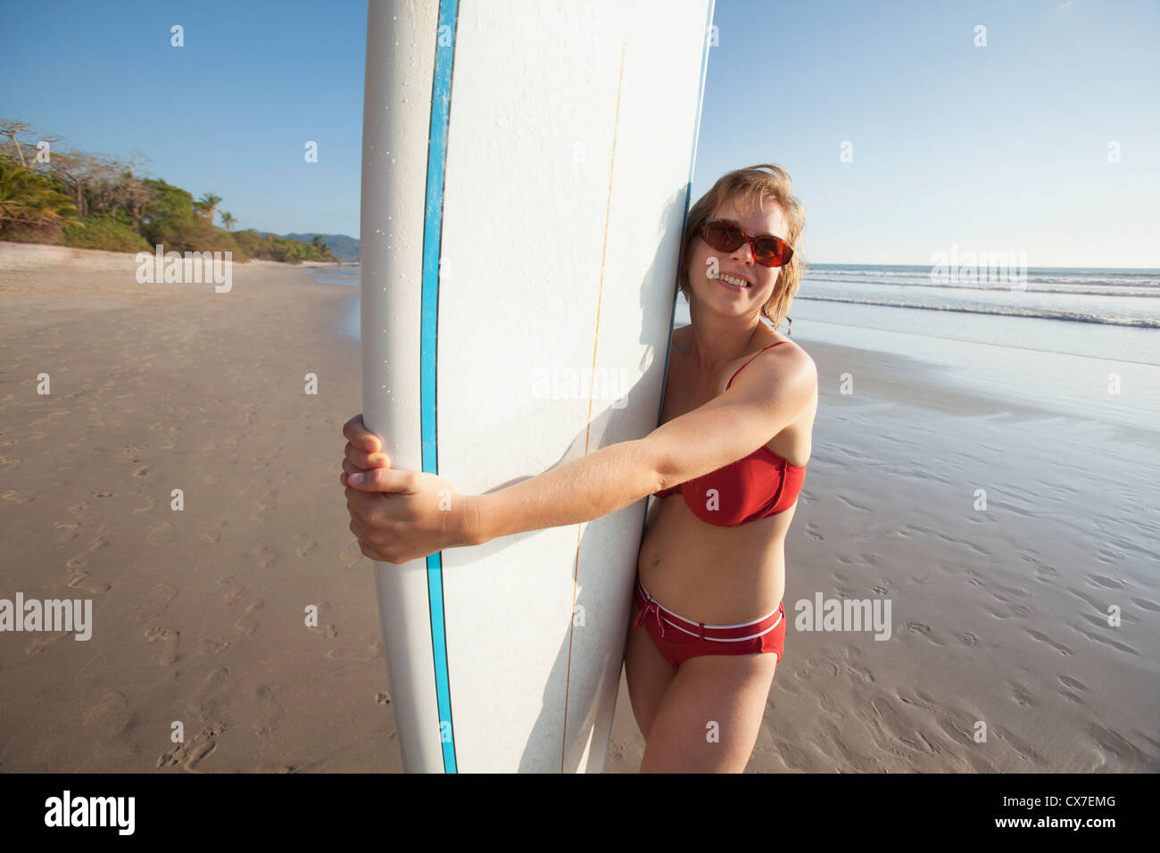 A woman holds her surfboard on playa santa teresa beach and mal pais on the nicoya peninsula;Puntarenas province costa rica Stock Photo