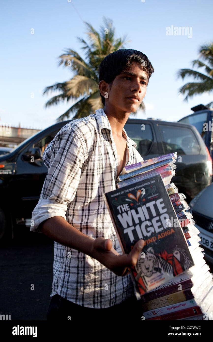 An Indian boy selling books to tourists in the traffic in Mumbai Stock Photo