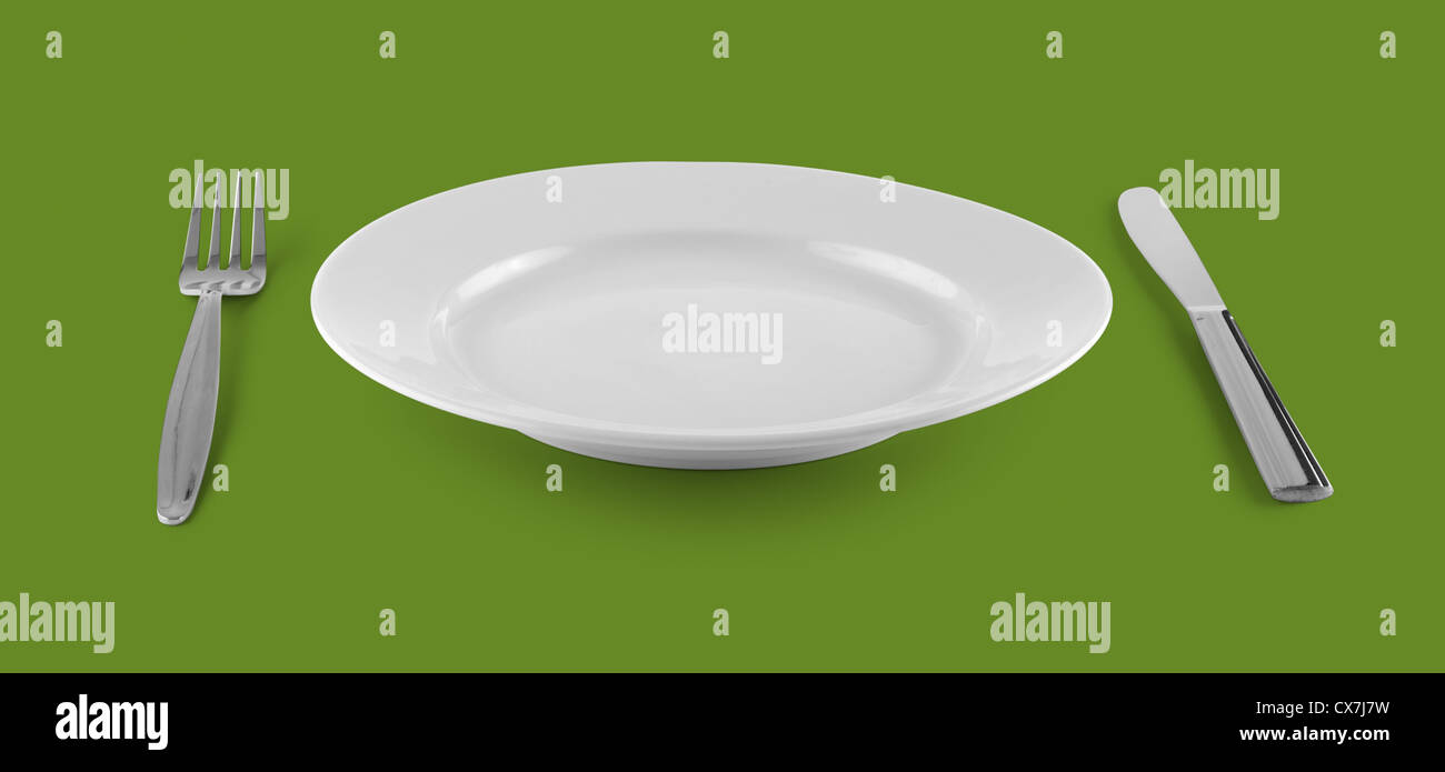 empty plate or dish for food with fork and knife on green table Stock Photo