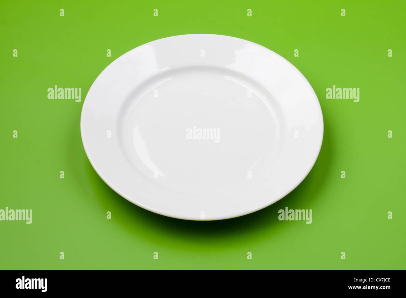 White round plate on green background Stock Photo