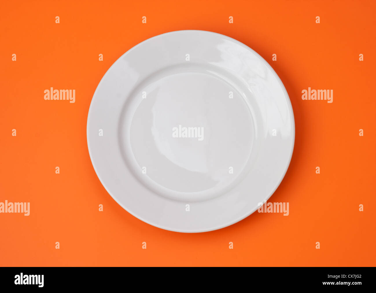 White round plate on orange background Stock Photo