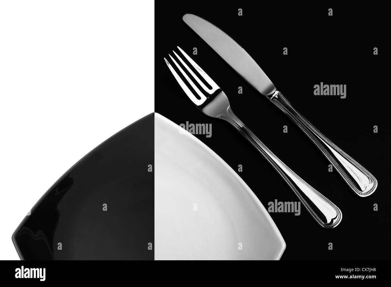 Knife, square white plate and fork on black background Stock Photo