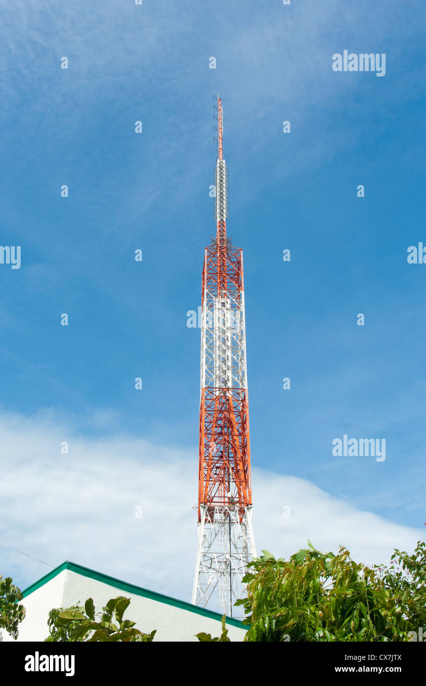 red with white radio tower against a blue sky Stock Photo