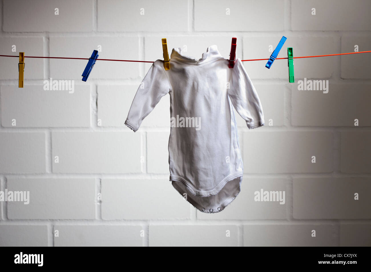 A baby's onesie hanging from a clothesline Stock Photo Alamy