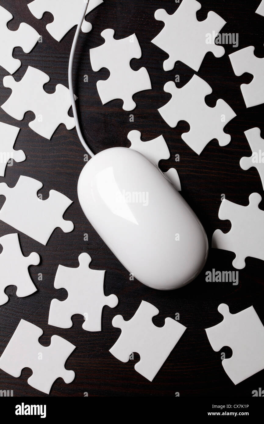 A computer mouse on top of jigsaw puzzle pieces Stock Photo